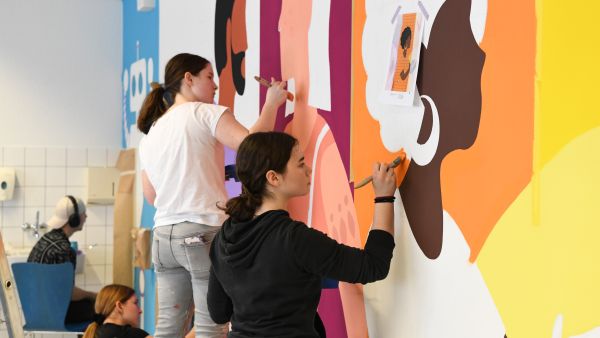 Mehrere Lernende am Malen der neuen Wandgestaltung